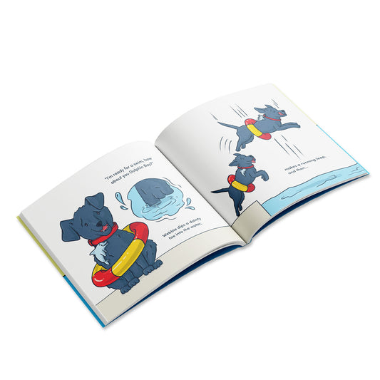 An open children’s book shows illustrated pages of a black dog wearing a red and yellow swim ring, jumping into a pool of water.