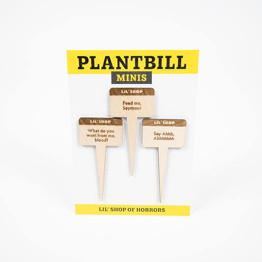 White and yellow card with "Plantbill Minis" across the top and "Lil' Shop of Horrors" across the bottom. In the middle are three wooden plant/garden stakes with "What do you want from me, blood?," "Feed me, Seymour," and "Sa Ahh, Ahhhhh" engraved on them.