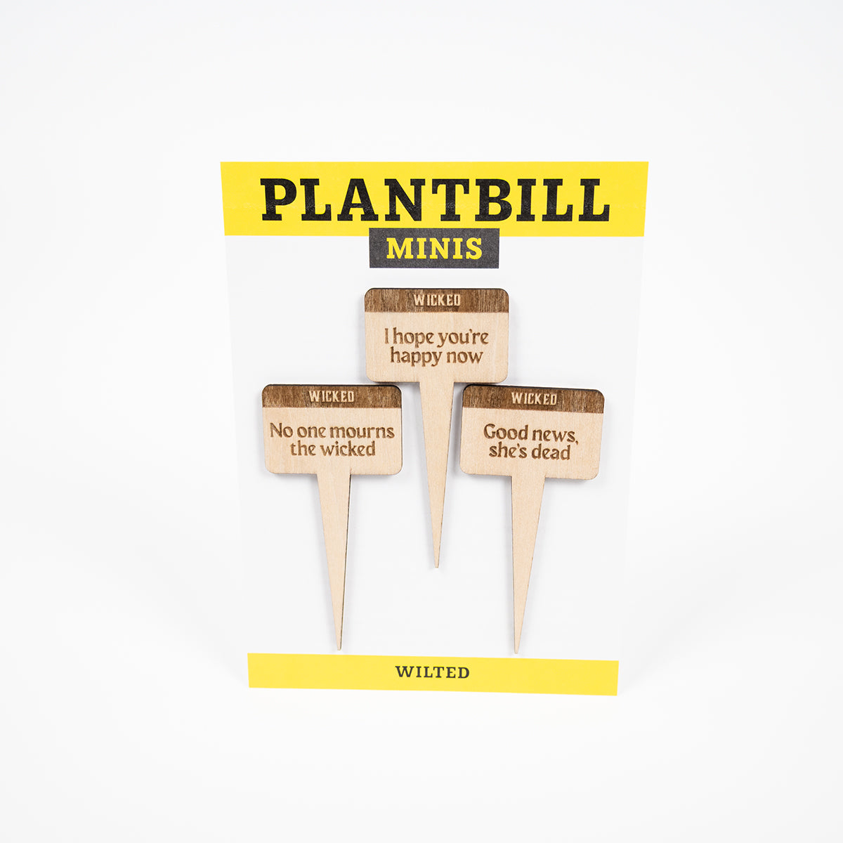 White and yellow card with "Plantbill Minis" across the top and "Wilted" across the bottom. In the middle are three wooden plant/garden stakes with "No one mourns the wicked," "I hope you're happy now," and "good news, she's dead" engraved on them.