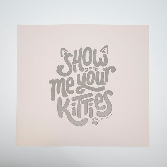 Square paper with hand lettered and illustrative "Show me your kitties" with cat ears, whiskers, and a paw print.