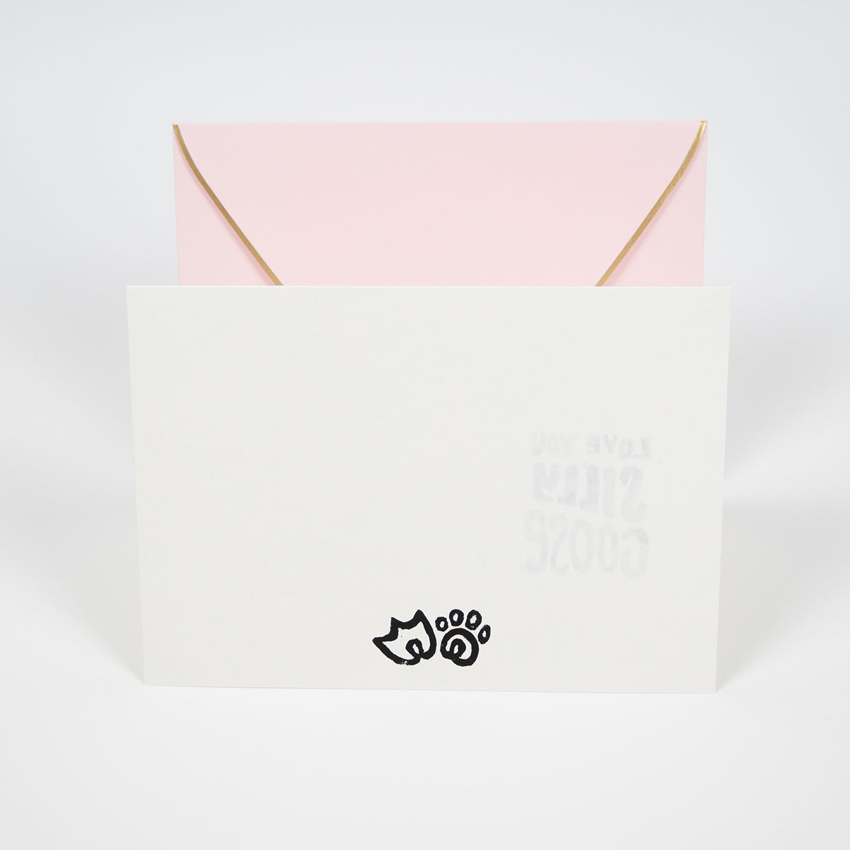 White greeting card with a duck foot and kitty paw illustrations in front of a light pink envelope.