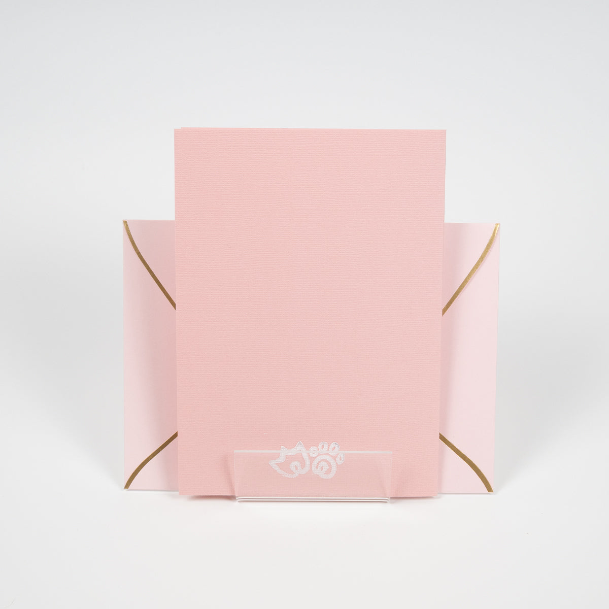 Light coral greeting card with a duck paw and cat paw illustration in front of a light pink envelope.