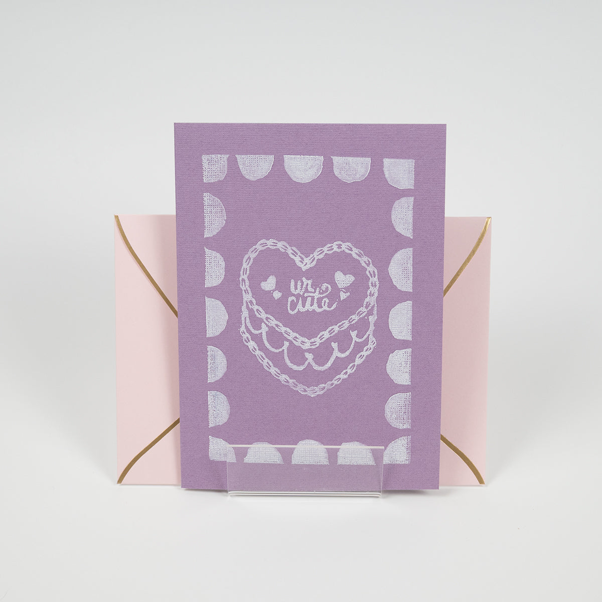 Purple greeting card with a"ur cute" cake illustration in front of a light pink envelope.
