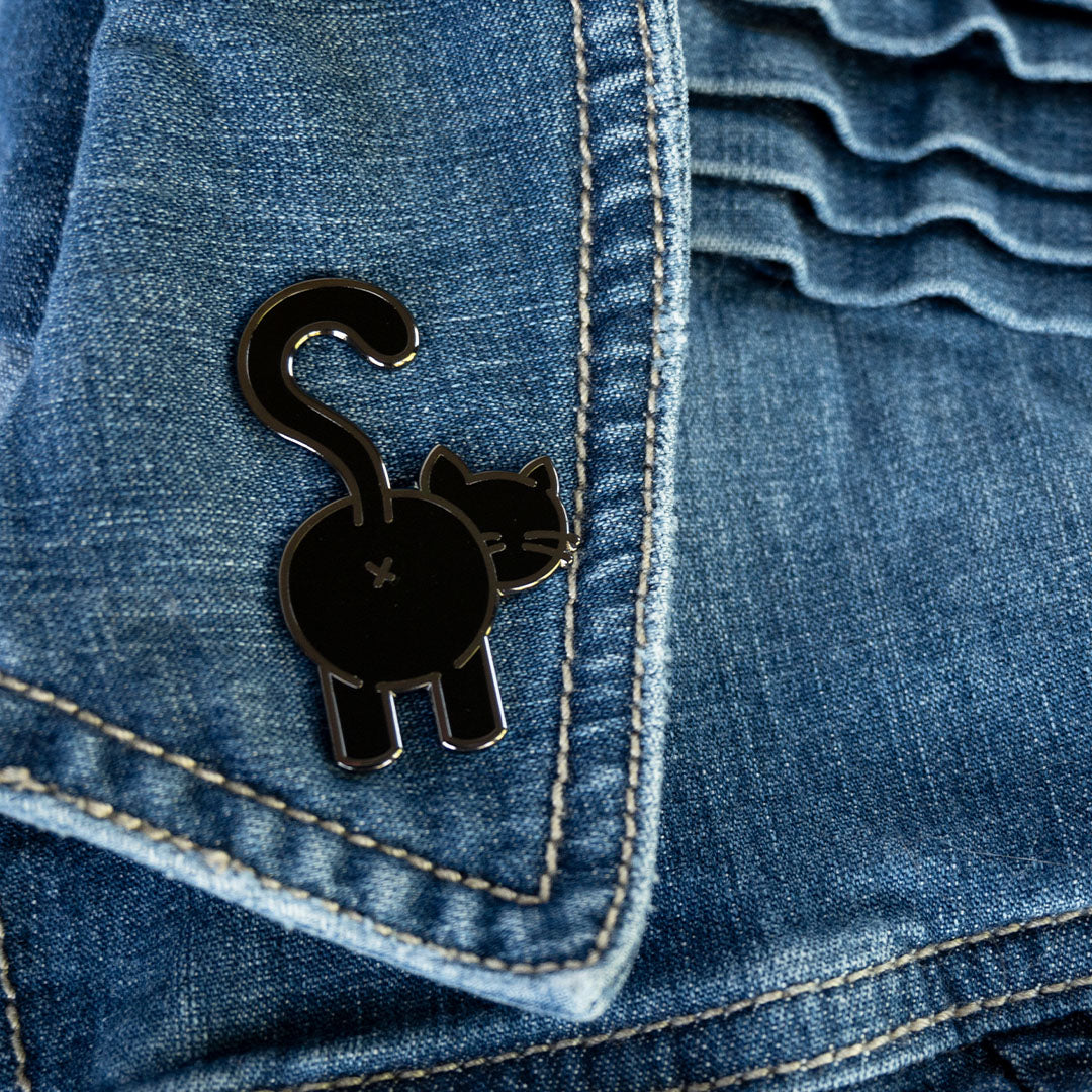 Black cat butt pin with black nickel metal attached to denim jacket lapel