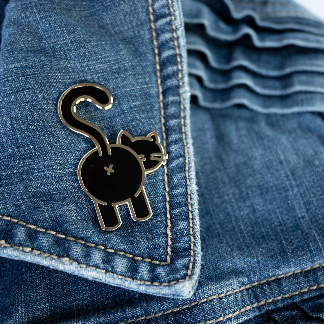 Black cat butt pin with silver metal attached to denim jacket lapel