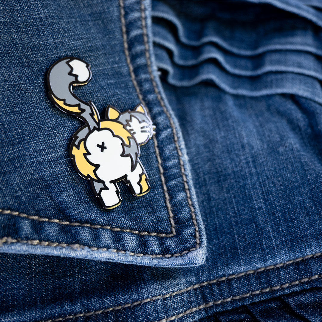 Light calico cat butt pin attached to denim jacket lapel.