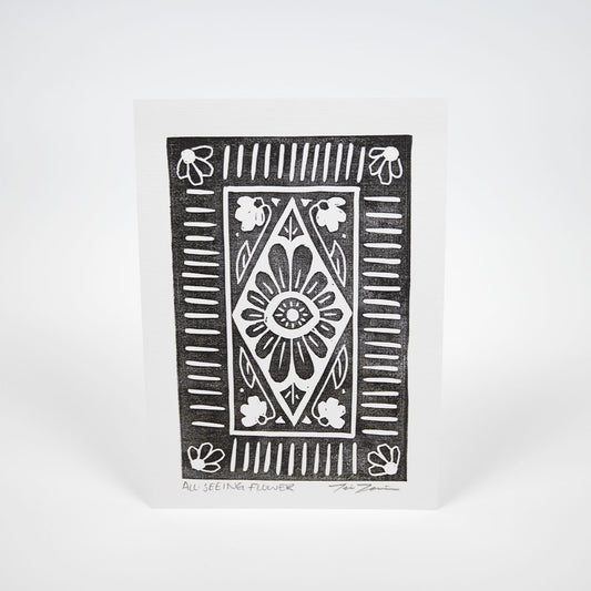 A black stylized illustration of a flower with an eye in the center surrounded by various lines and flowers on white paper. 
