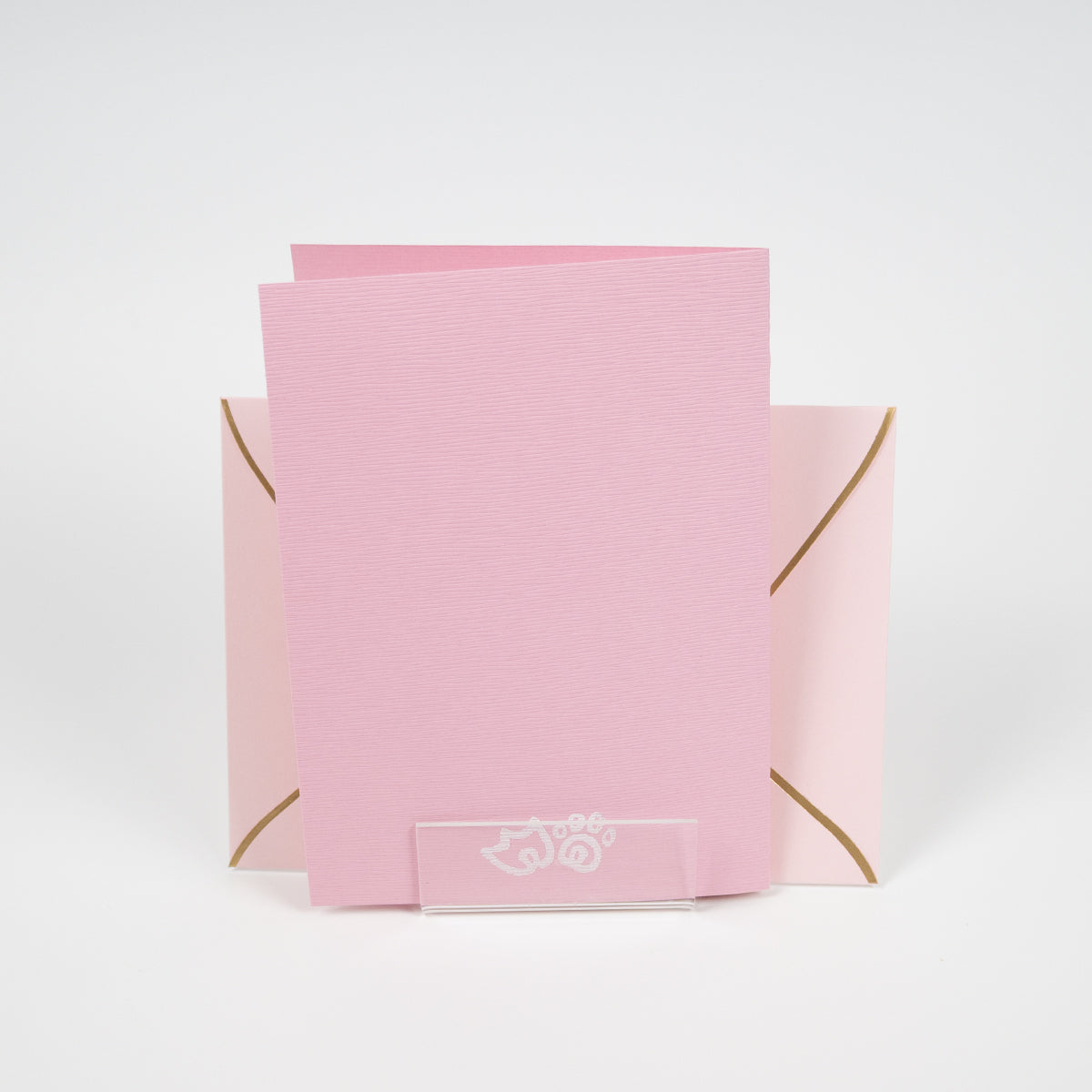 Light pink greeting card with a duck paw and cat paw illustration in front of a light pink envelope. 